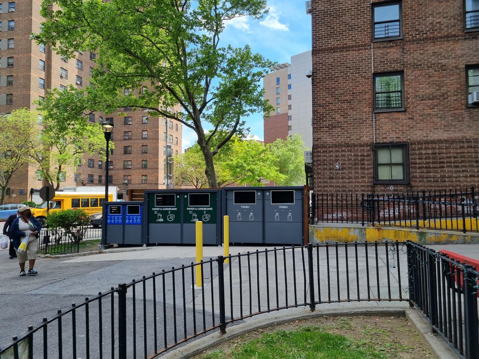 Waste enclosures in different colors, in front of brick building