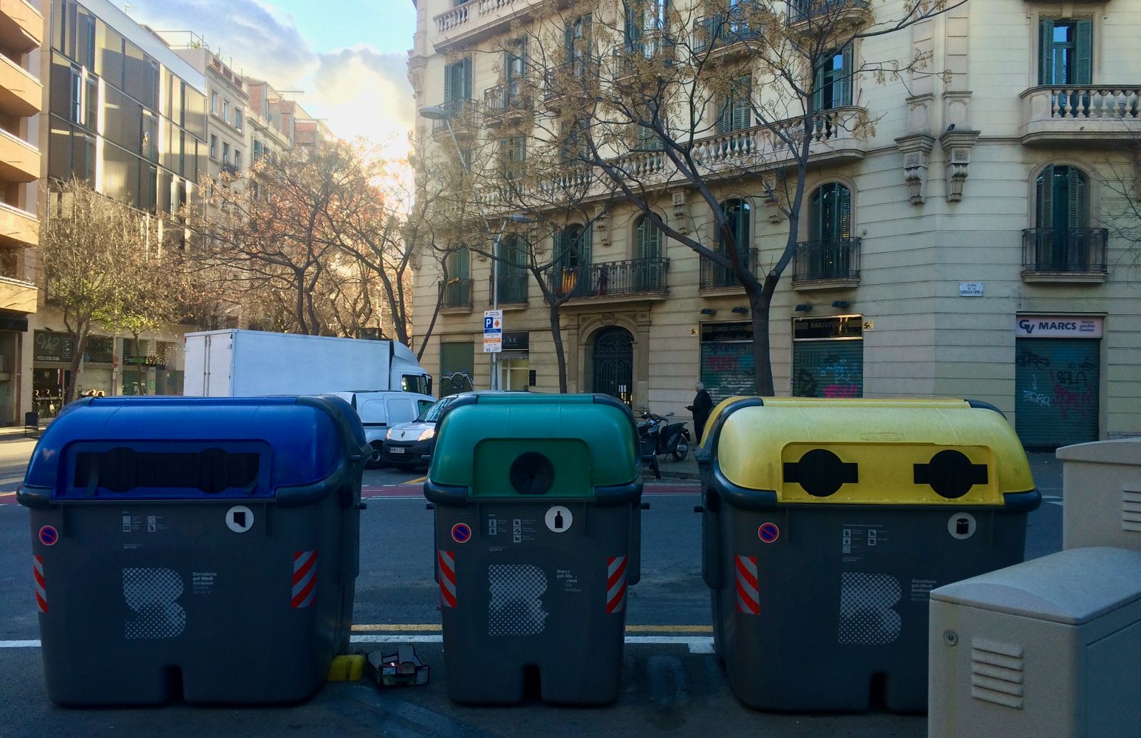 Three colorful shared waste and recycling containers on the streets of Barcelona